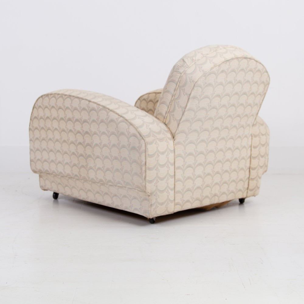 A pair of 1930s Art Deco upholstered armchairs featuring rounded arms, a scalloped fabric pattern, and small integrated casters. View X