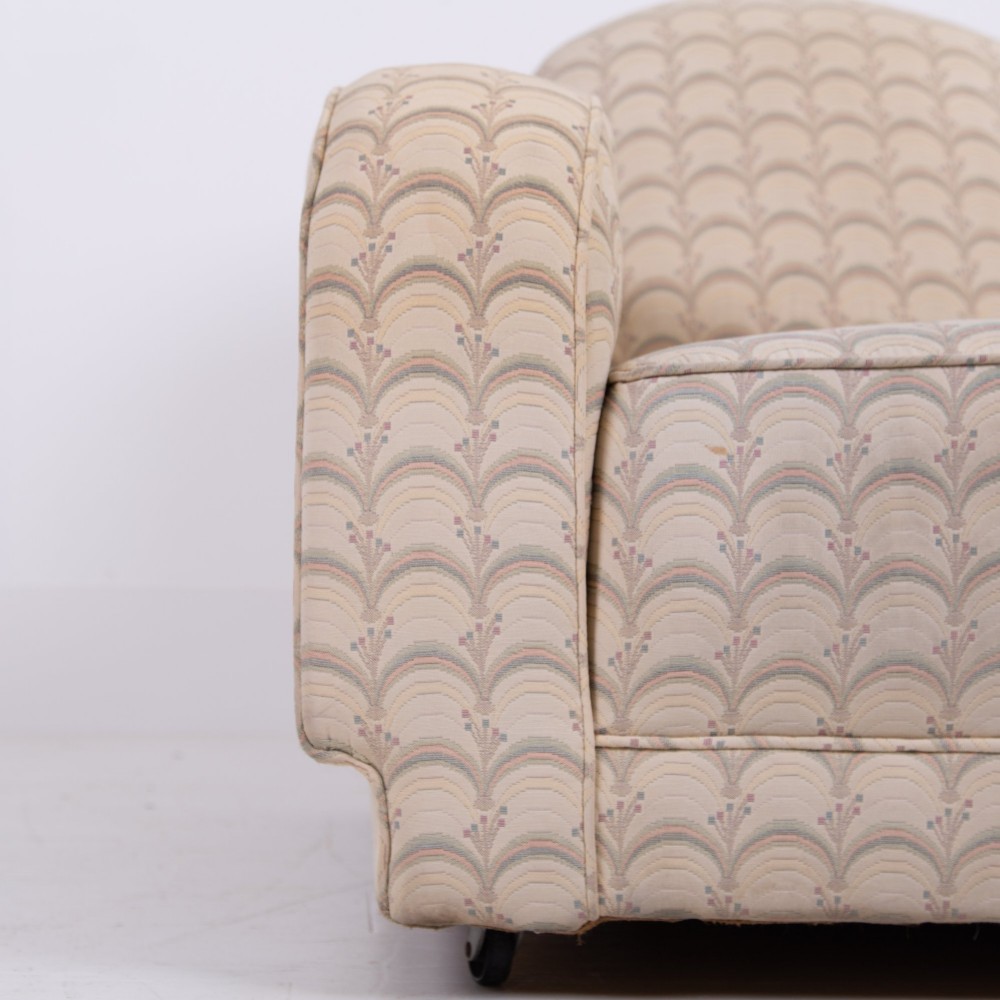 A pair of 1930s Art Deco upholstered armchairs featuring rounded arms, a scalloped fabric pattern, and small integrated casters. View XII