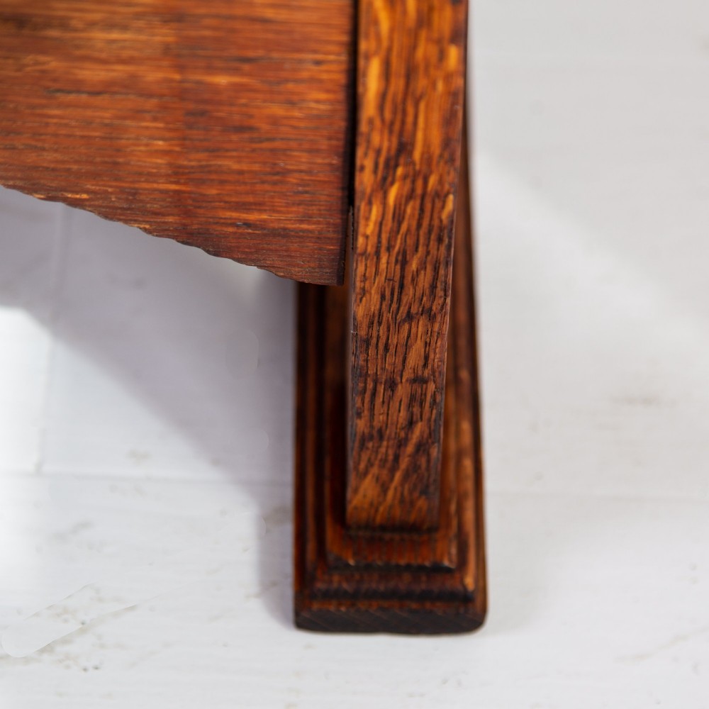 An Arts and Crafts oak hall wardrobe featuring a central mirrored door, dark glass roundel inserts near the top, and an arched apron base. View VIII