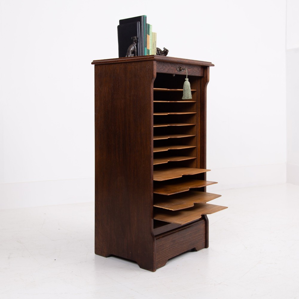 A tall dark oak filing cabinet with a vertical tambour slatted roller shutter door and brass lock plate. View II