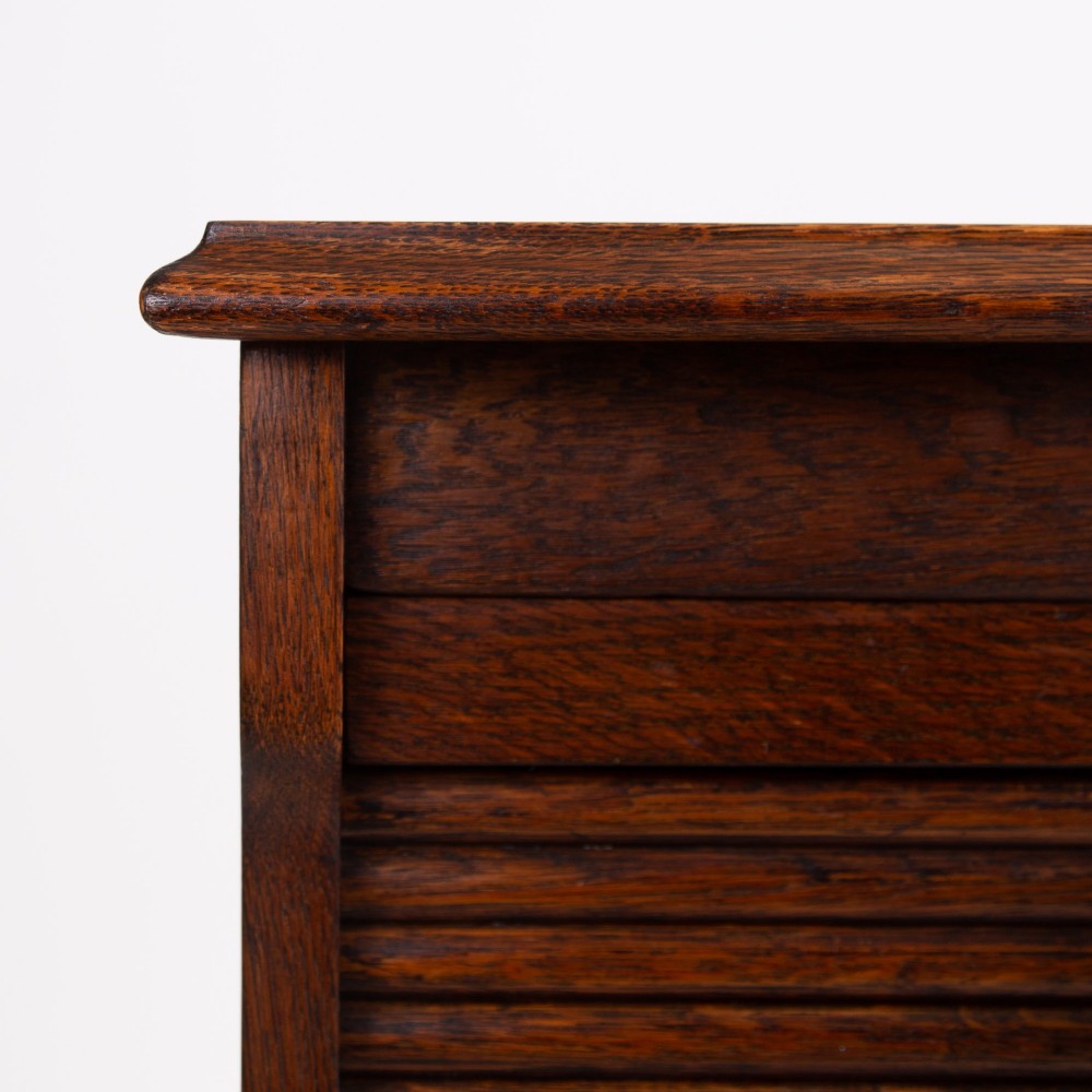 A tall dark oak filing cabinet with a vertical tambour slatted roller shutter door and brass lock plate. View IX