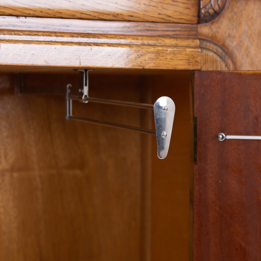 A 1930s Art Deco oak bachelors wardrobe featuring a top drawer, a central cupboard door with rounded framing, and carved corner accents. View VII