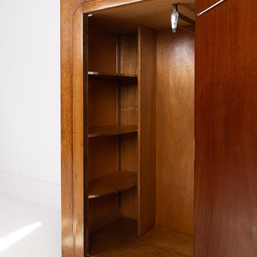 A 1930s Art Deco oak bachelors wardrobe featuring a top drawer, a central cupboard door with rounded framing, and carved corner accents. View VIII