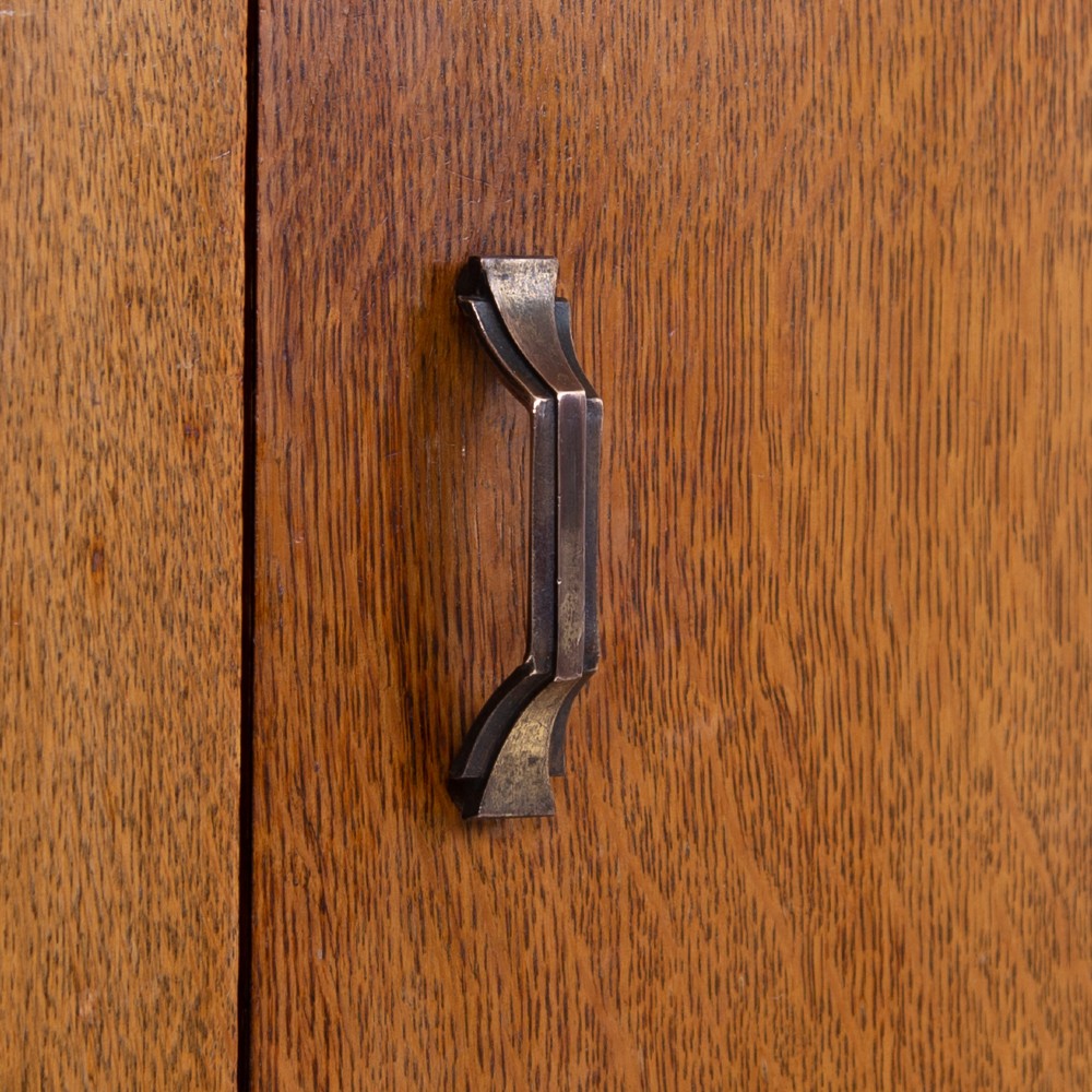 A 1930s Art Deco oak bachelors wardrobe featuring a top drawer, a central cupboard door with rounded framing, and carved corner accents. View X