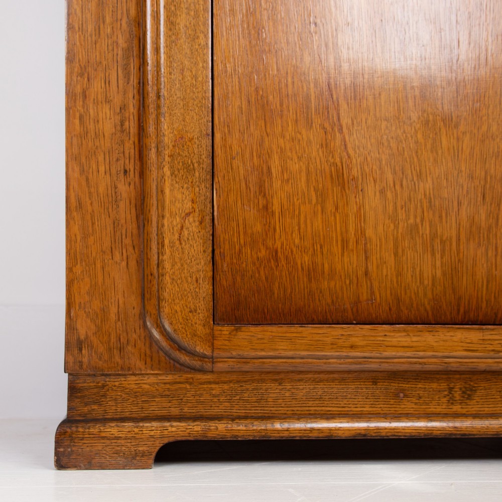 A 1930s Art Deco oak bachelors wardrobe featuring a top drawer, a central cupboard door with rounded framing, and carved corner accents. View XIV