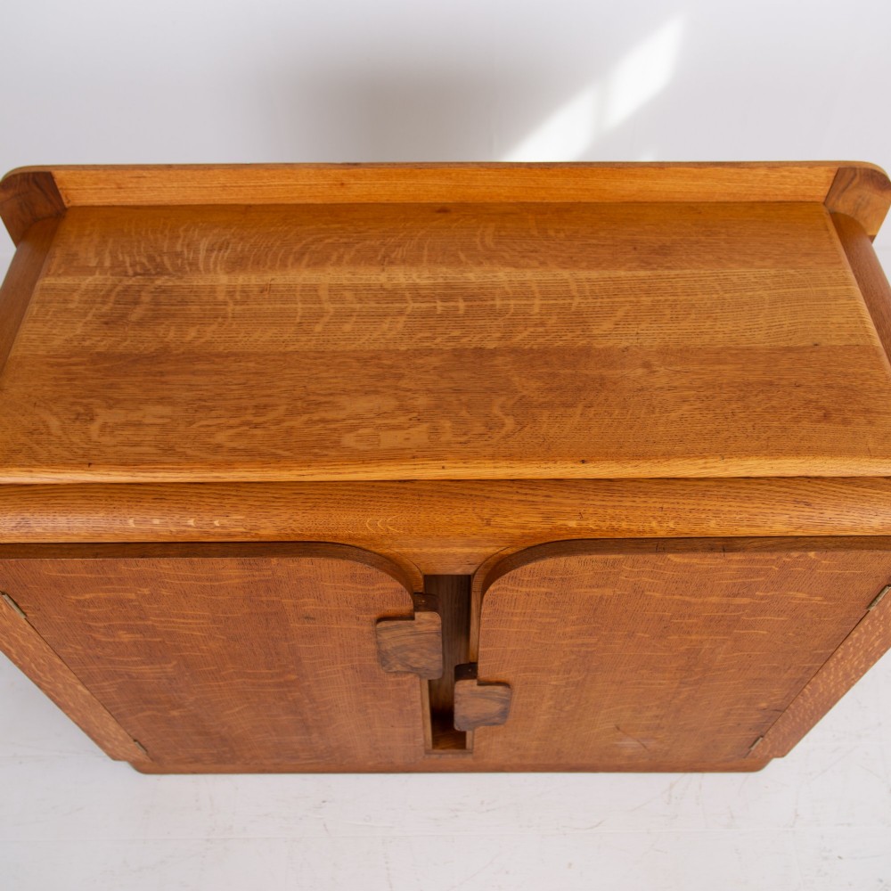 An Art Deco golden oak sideboard cabinet featuring rounded top edges, quarter-sawn wood grain, two central doors with wooden block handles, and a solid base plinth. View IX