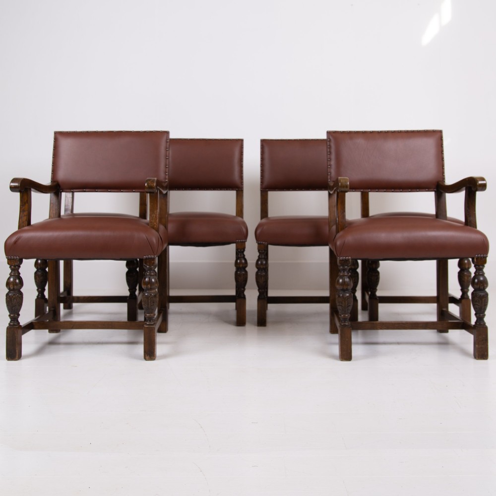 A set of six dark oak dining chairs featuring brown leather upholstered seats and backrests with brass stud detailing and turned front legs. View II