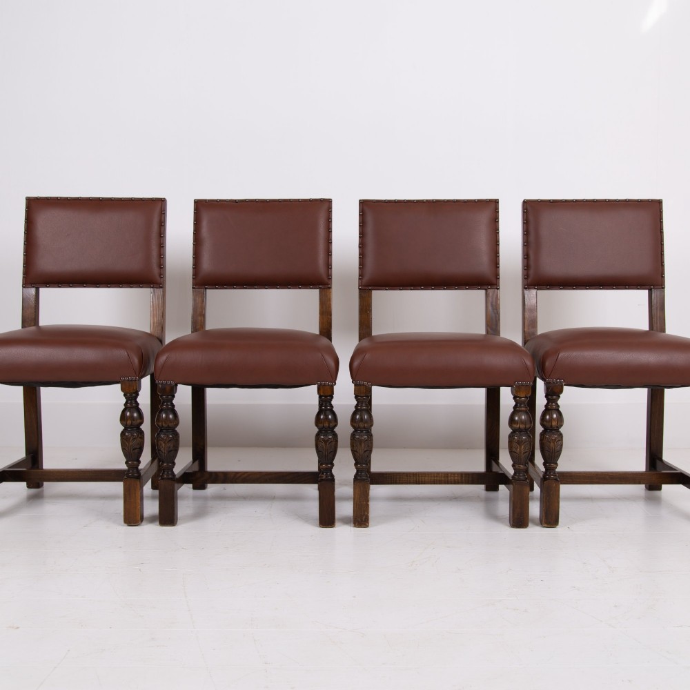 A set of six dark oak dining chairs featuring brown leather upholstered seats and backrests with brass stud detailing and turned front legs. View III