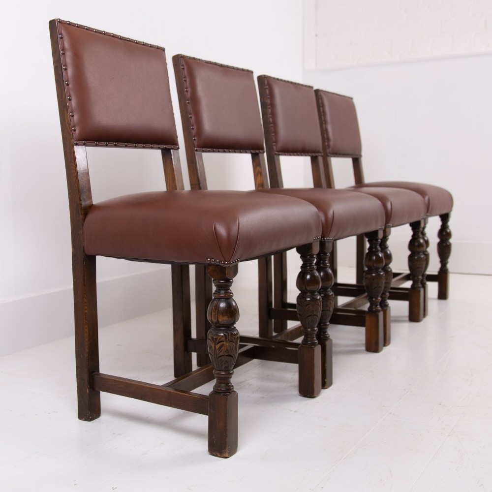 A set of six dark oak dining chairs featuring brown leather upholstered seats and backrests with brass stud detailing and turned front legs. View IV