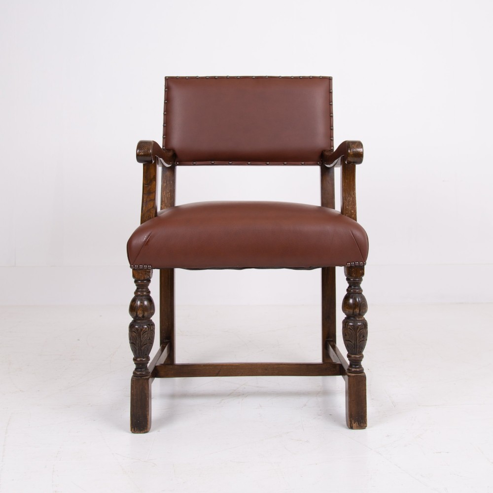 A set of six dark oak dining chairs featuring brown leather upholstered seats and backrests with brass stud detailing and turned front legs. View VII