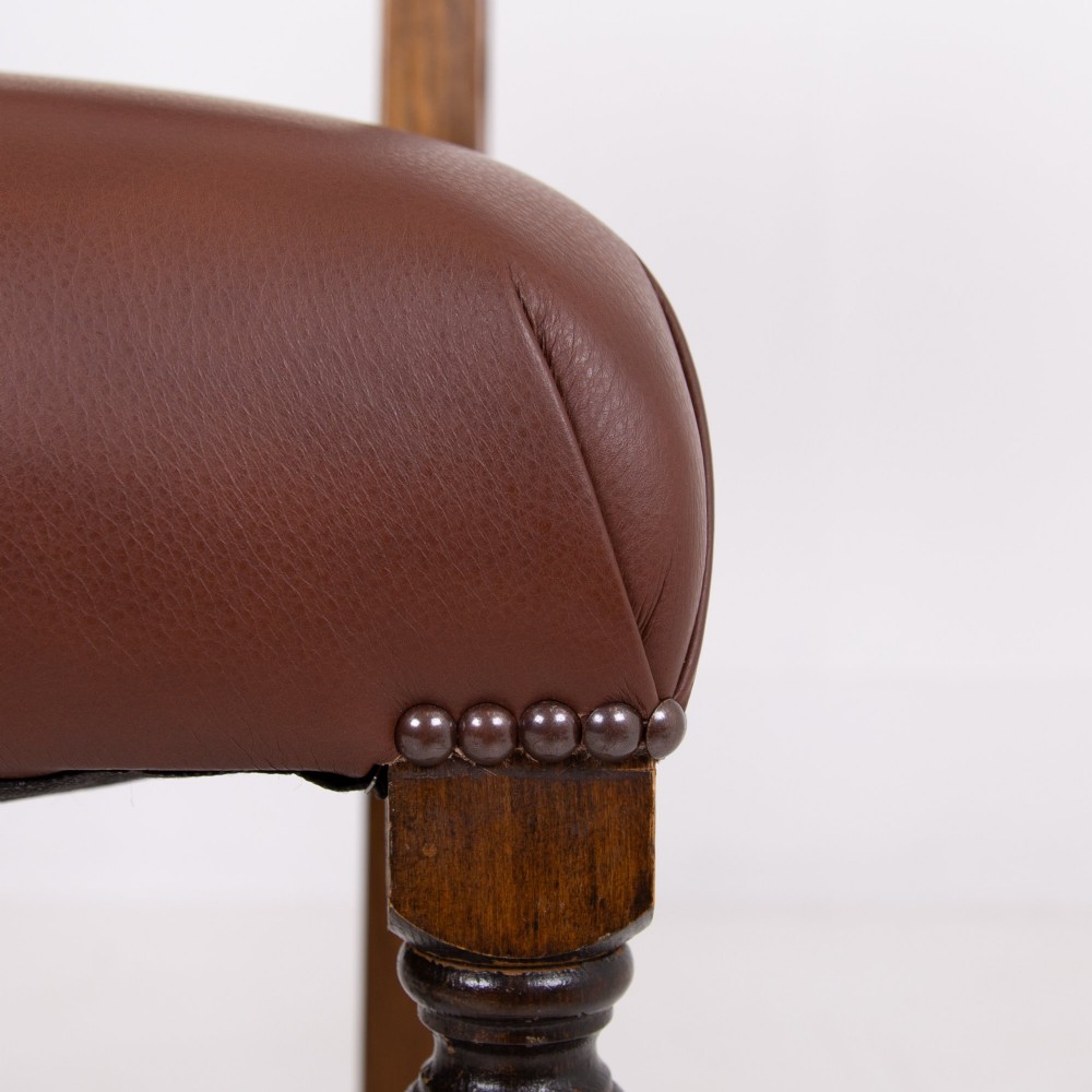 A set of six dark oak dining chairs featuring brown leather upholstered seats and backrests with brass stud detailing and turned front legs. View XIV