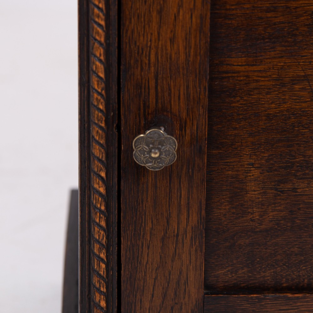 A small late Victorian dark oak bookcase featuring two open shelves above a single cupboard door with carved rope-twist moulding and a solid plinth base. View VII