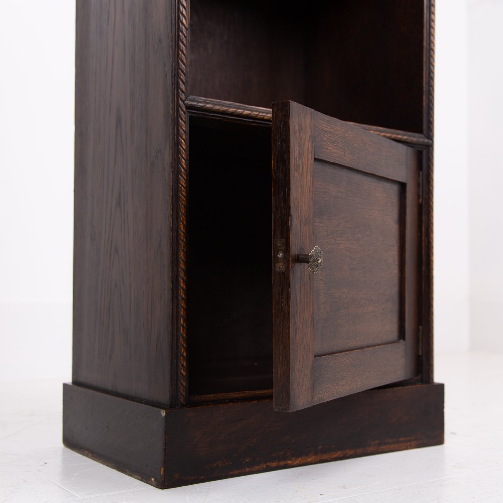 A small late Victorian dark oak bookcase featuring two open shelves above a single cupboard door with carved rope-twist moulding and a solid plinth base. View VIII