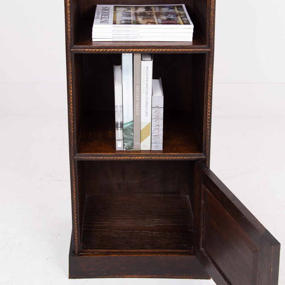 A small late Victorian dark oak bookcase featuring two open shelves above a single cupboard door with carved rope-twist moulding and a solid plinth base. View X