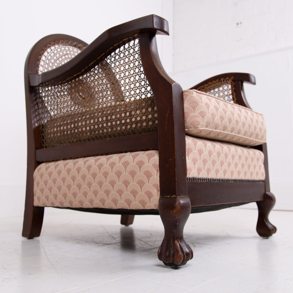 A pair of 1920s dark wood bergere armchairs featuring circular woven cane backs, cane sides, and pink fan-pattern upholstered cushions. View XII
