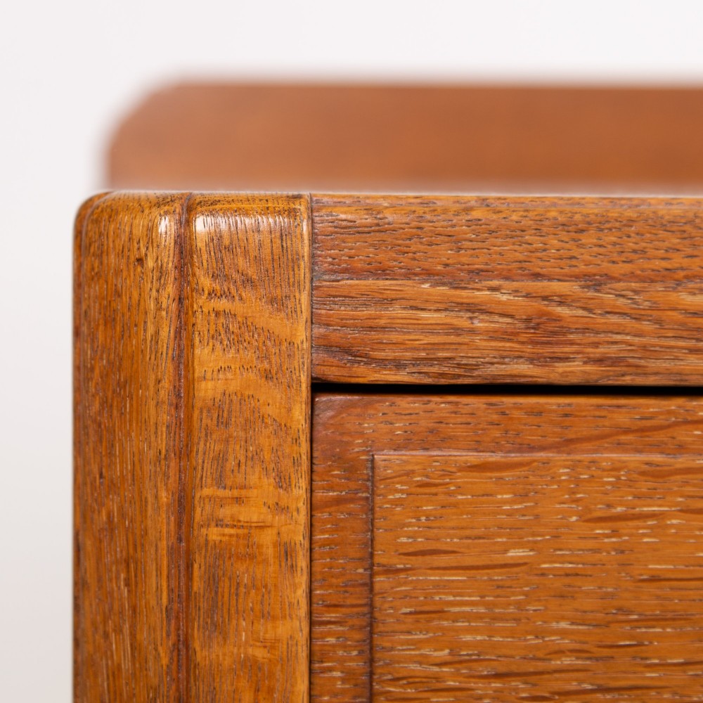 A 1930s light oak sideboard featuring three upper drawers over three panelled cupboard doors with wooden knob handles. View VI