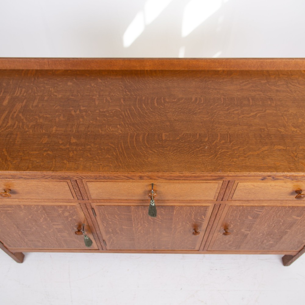 A 1930s light oak sideboard featuring three upper drawers over three panelled cupboard doors with wooden knob handles. View VIII