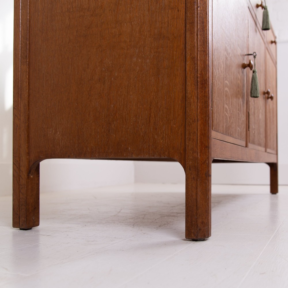 A 1930s light oak sideboard featuring three upper drawers over three panelled cupboard doors with wooden knob handles. View IX