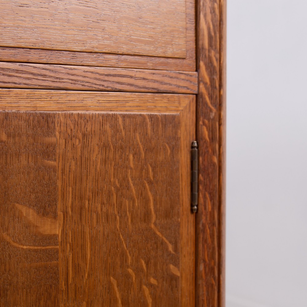 A 1930s light oak sideboard featuring three upper drawers over three panelled cupboard doors with wooden knob handles. View X
