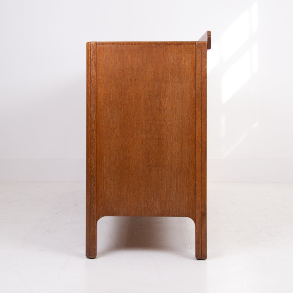 A 1930s light oak sideboard featuring three upper drawers over three panelled cupboard doors with wooden knob handles. View XII