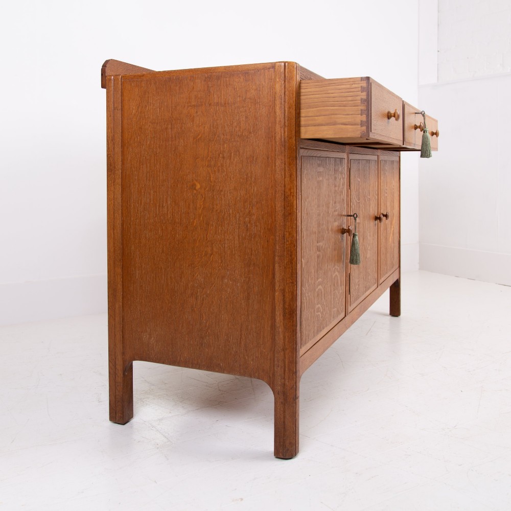 A 1930s light oak sideboard featuring three upper drawers over three panelled cupboard doors with wooden knob handles. View XIII