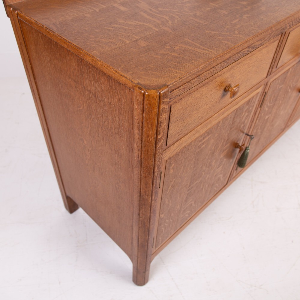 A 1930s light oak sideboard featuring three upper drawers over three panelled cupboard doors with wooden knob handles. View XIV