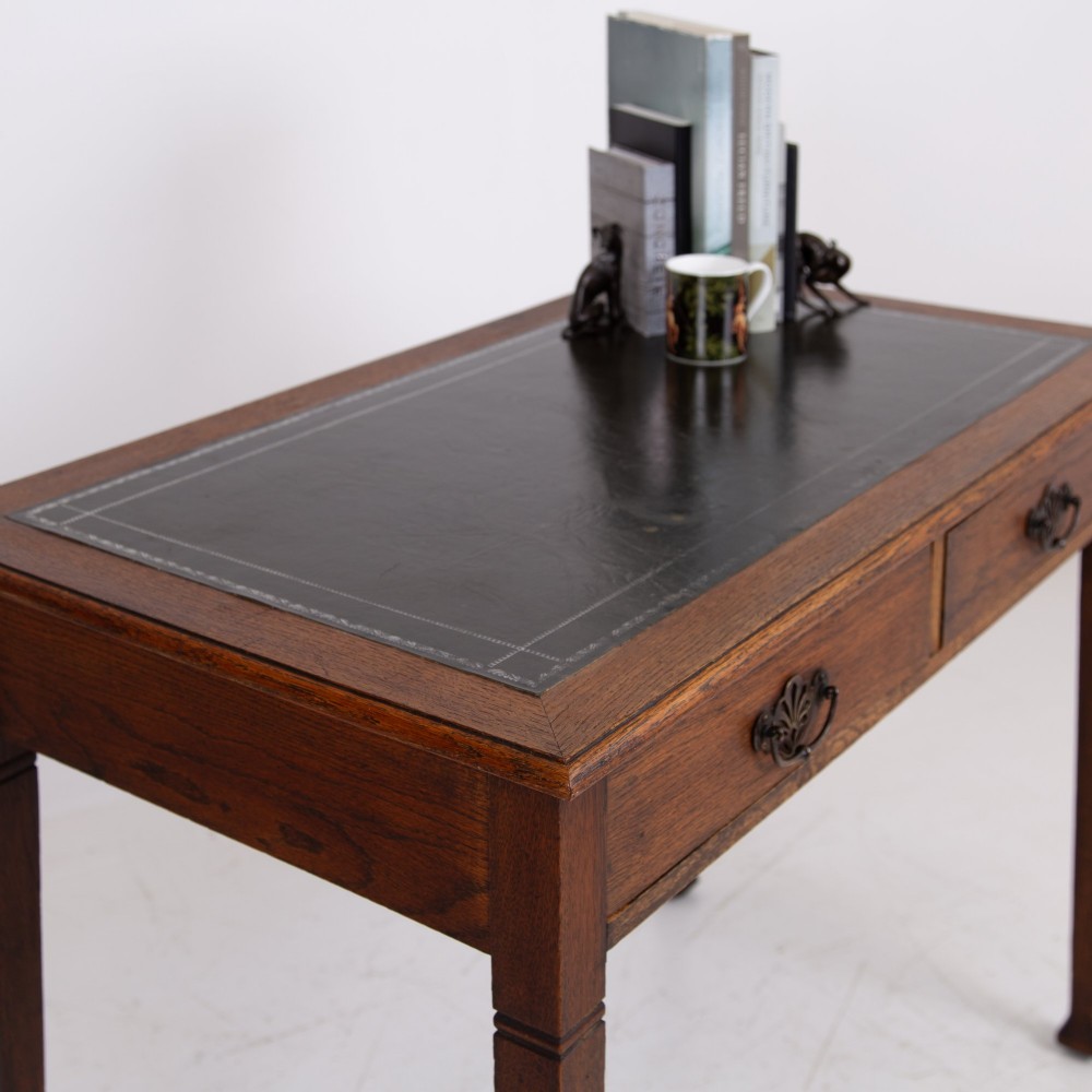 A 1920s English oak writing table featuring two frieze drawers with metal drop handles and four slender tapered legs. View II