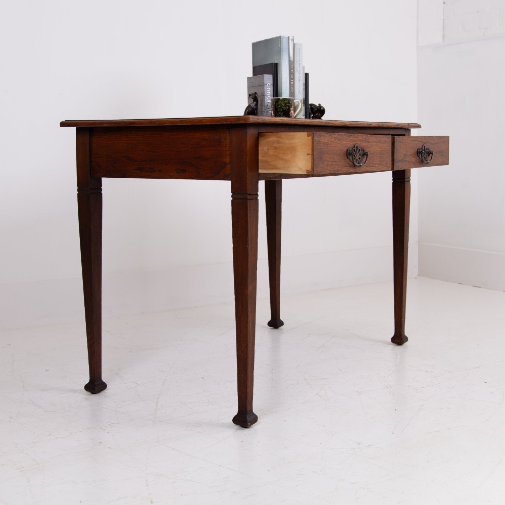 A 1920s English oak writing table featuring two frieze drawers with metal drop handles and four slender tapered legs. View III
