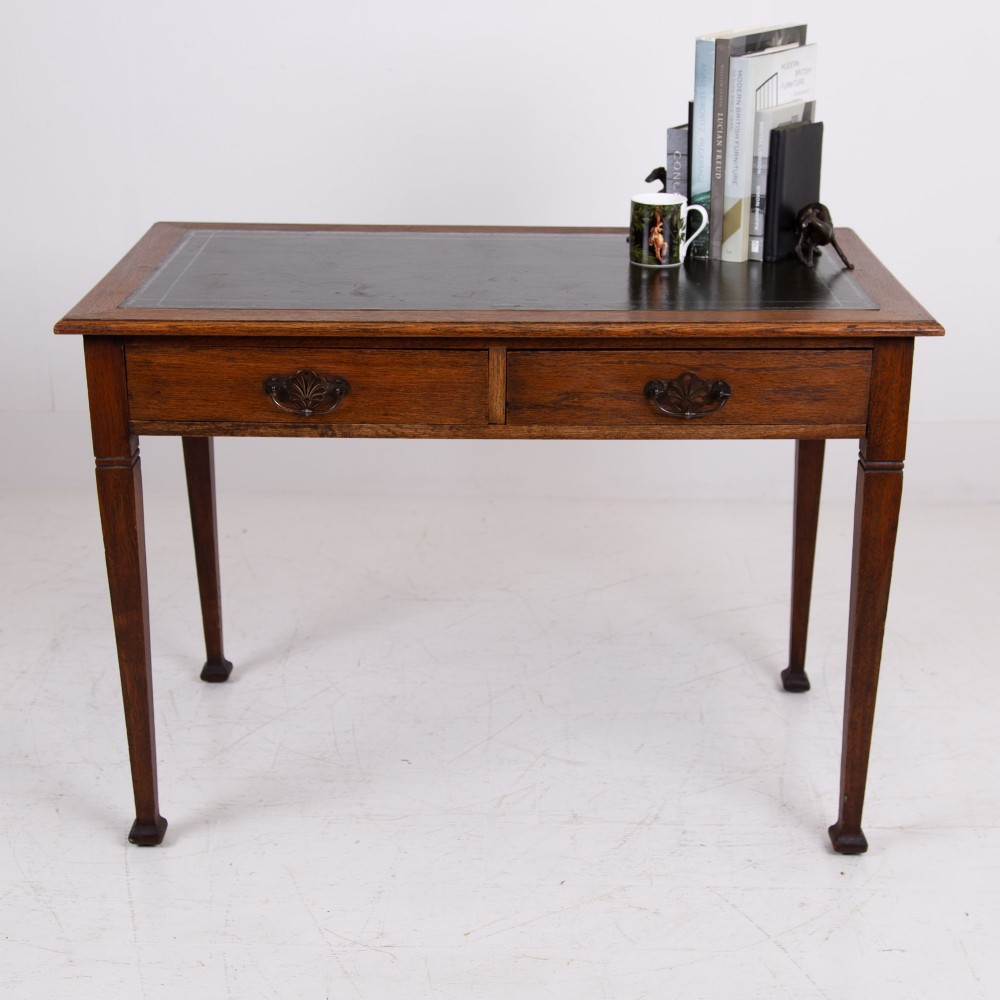 A 1920s English oak writing table featuring two frieze drawers with metal drop handles and four slender tapered legs. View IV
