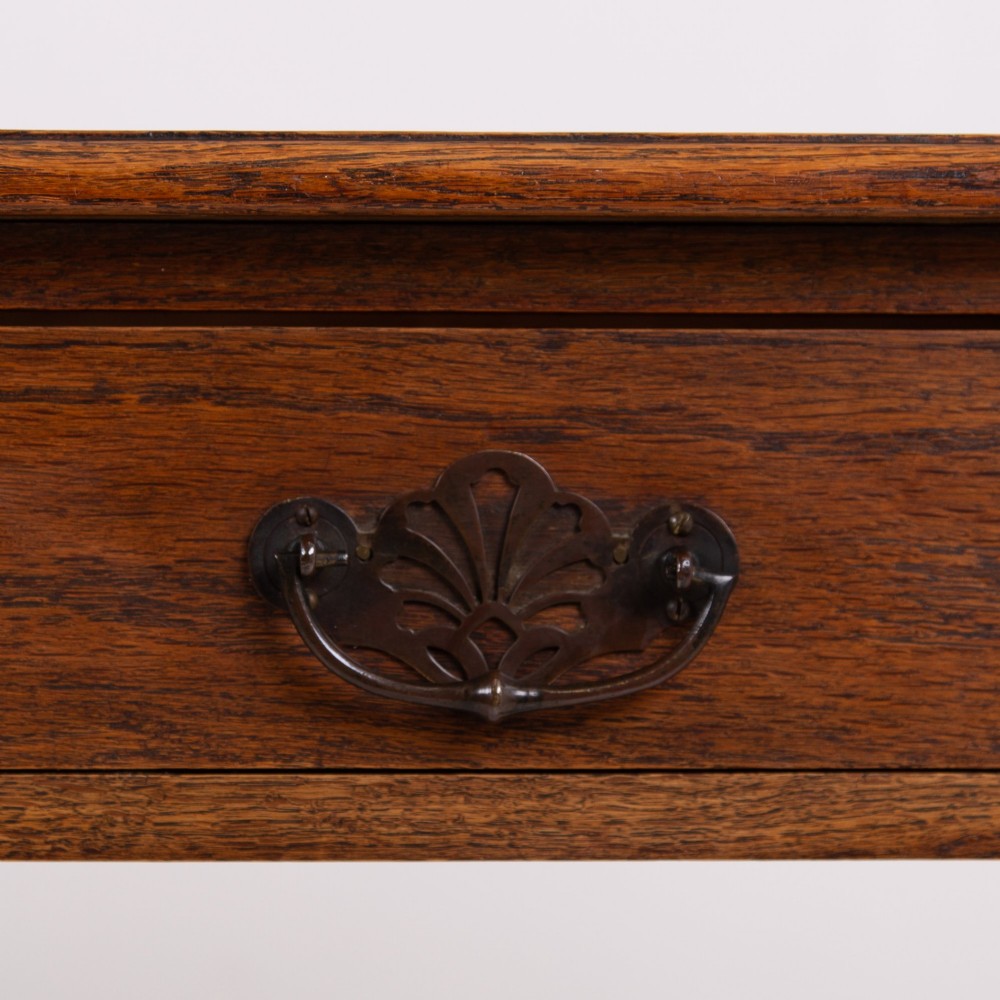 A 1920s English oak writing table featuring two frieze drawers with metal drop handles and four slender tapered legs. View V
