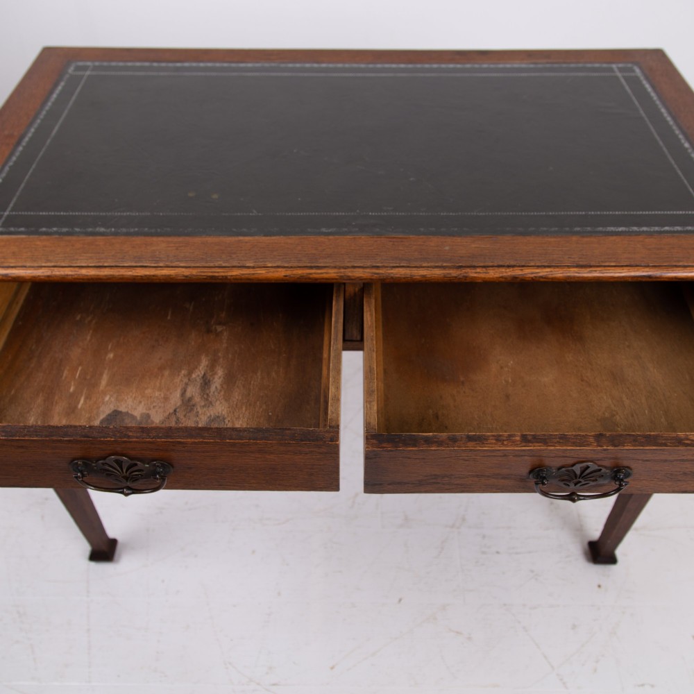 A 1920s English oak writing table featuring two frieze drawers with metal drop handles and four slender tapered legs. View VIII