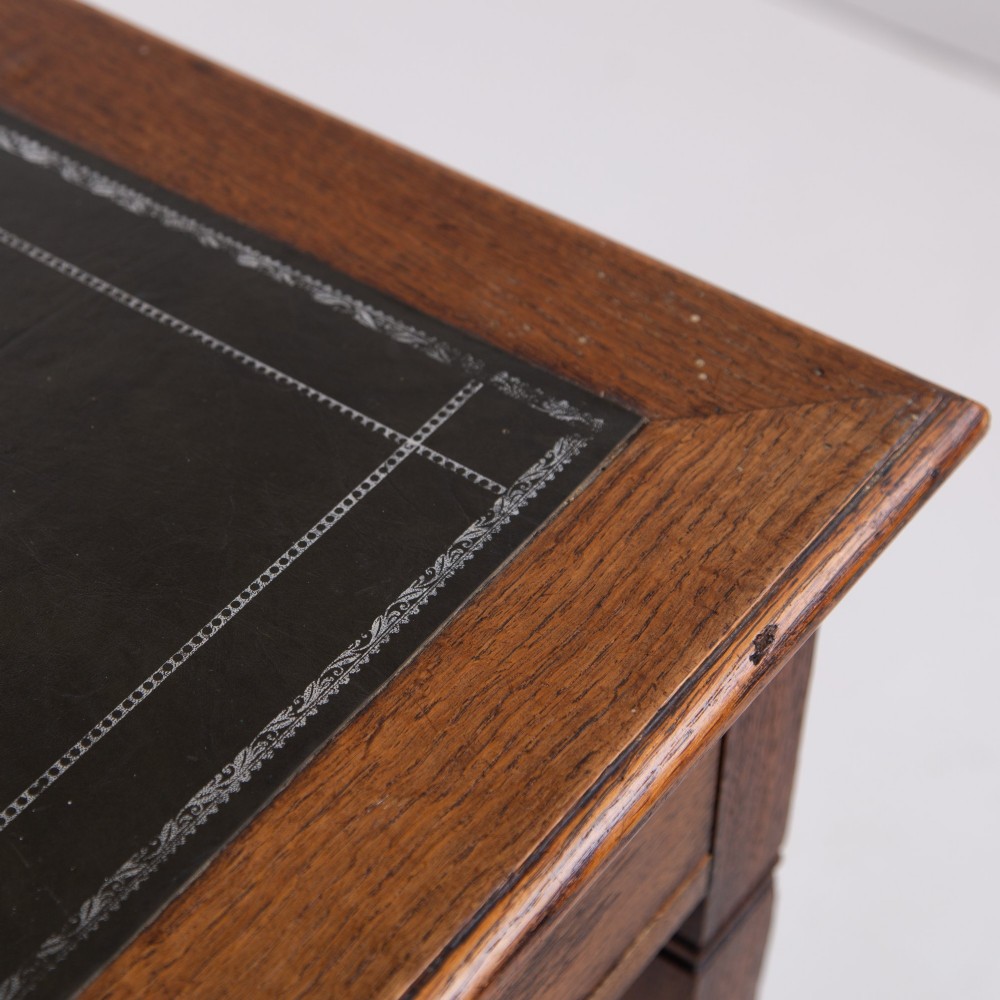 A 1920s English oak writing table featuring two frieze drawers with metal drop handles and four slender tapered legs. View X