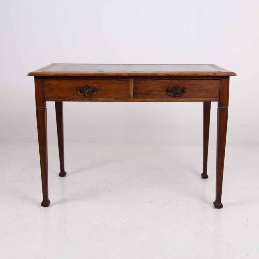 A 1920s English oak writing table featuring two frieze drawers with metal drop handles and four slender tapered legs. View XII
