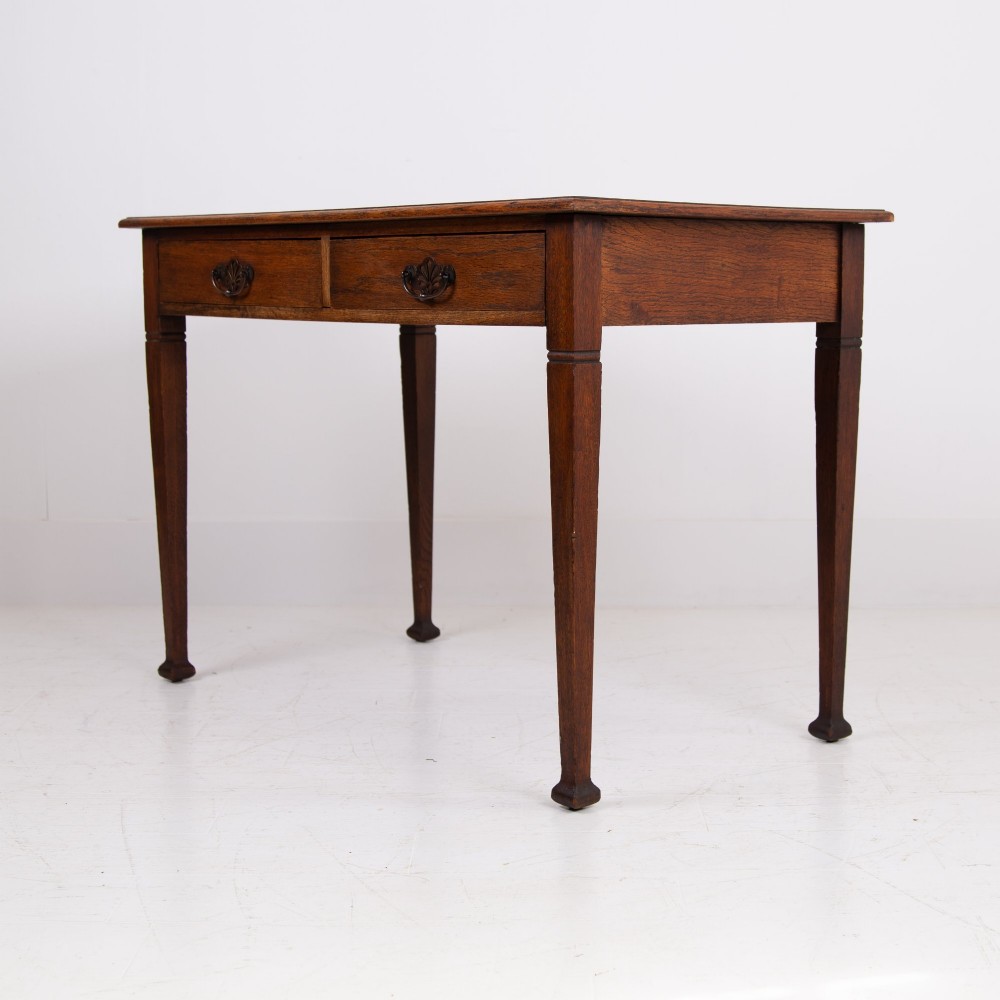 A 1920s English oak writing table featuring two frieze drawers with metal drop handles and four slender tapered legs. View XIV