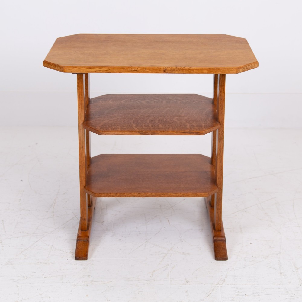 An antique Cotswold School solid oak side table featuring three rectangular shelves supported by straight uprights and sled feet. View IV