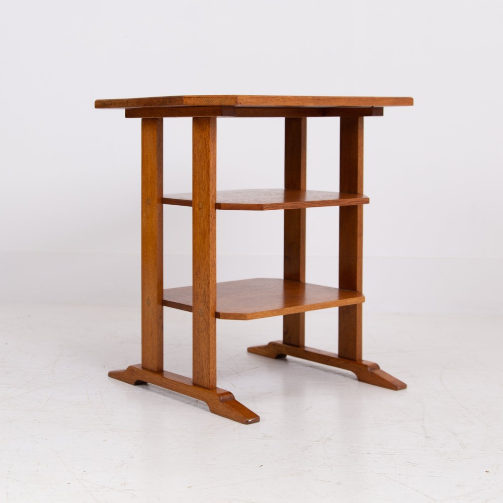 An antique Cotswold School solid oak side table featuring three rectangular shelves supported by straight uprights and sled feet. View VIII