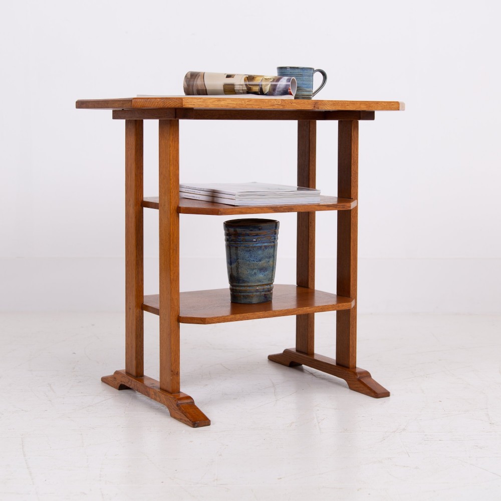 An antique Cotswold School solid oak side table featuring three rectangular shelves supported by straight uprights and sled feet. View XIII