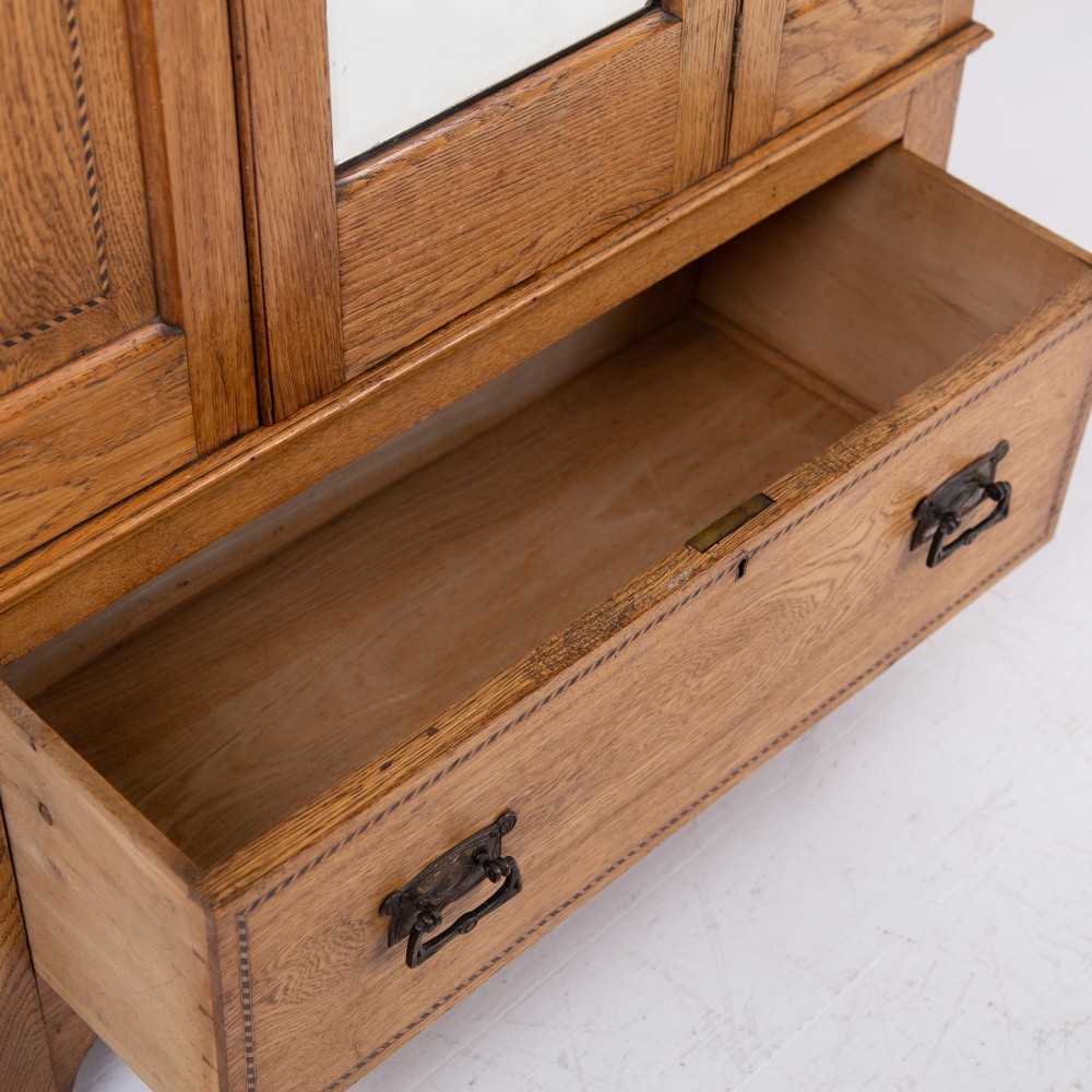 An Edwardian single-door oak wardrobe featuring a central vertical mirror, recessed side panels, a single base drawer, and a stepped top cornice. View IX
