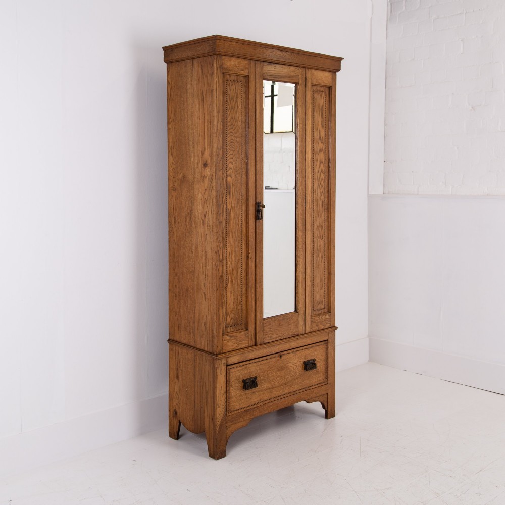 An Edwardian single-door oak wardrobe featuring a central vertical mirror, recessed side panels, a single base drawer, and a stepped top cornice. View XIII