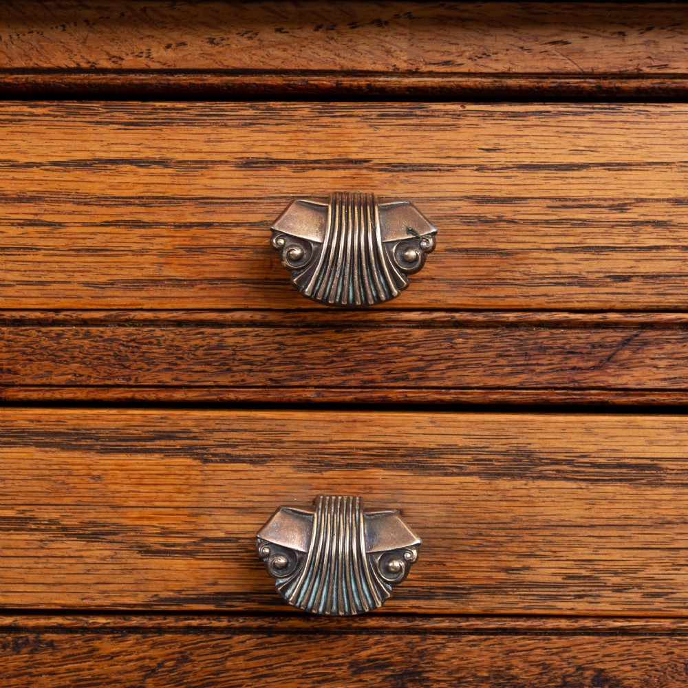A warm brown oak side table featuring two stacked drawers with metal shell handles, four turned barley twist legs, and a low rectangular shelf. View IV