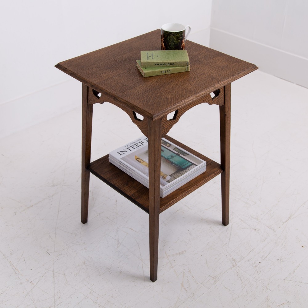 An Arts and Crafts solid oak two-tier side table with tapered legs and heart-shaped pierced motifs along the apron. View III