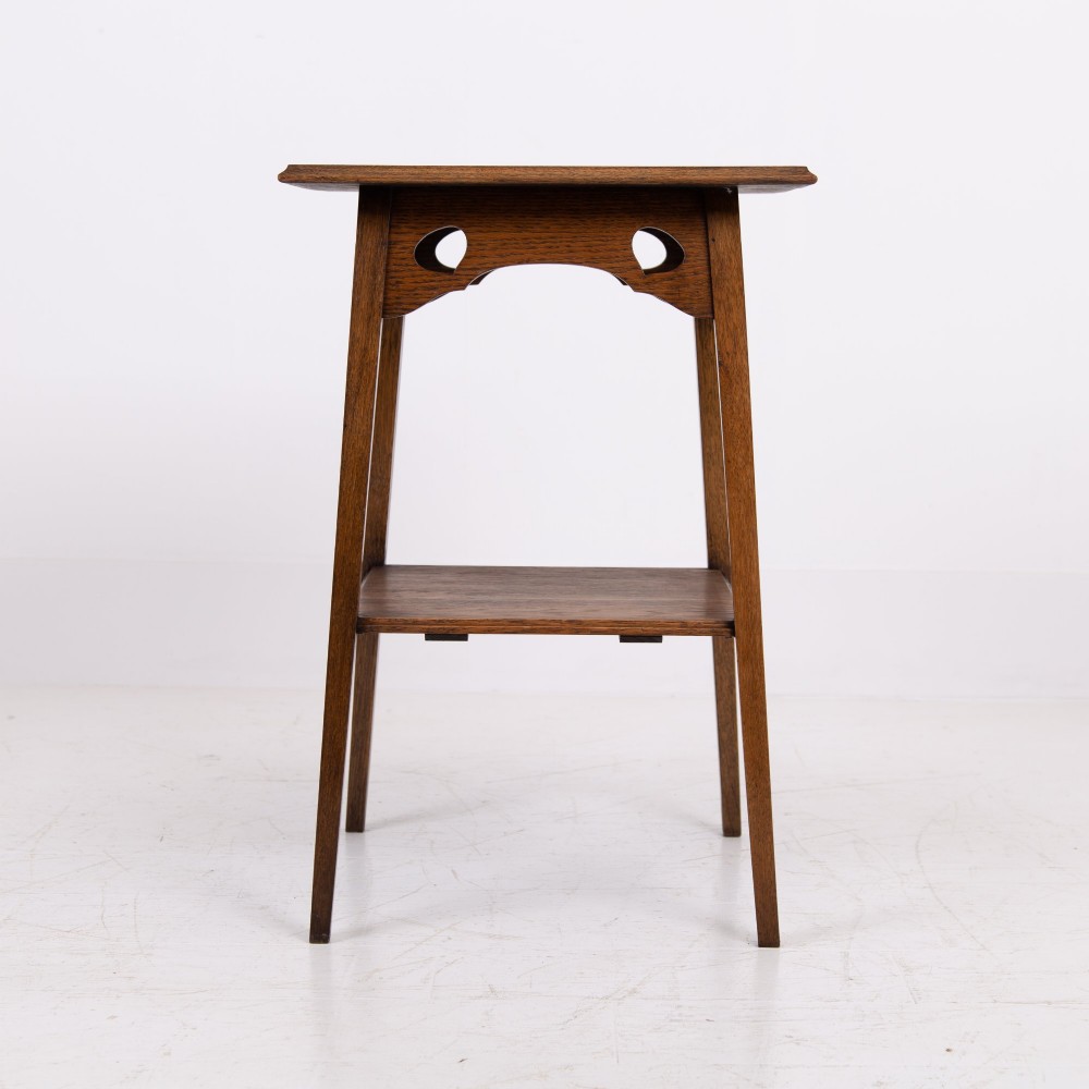 An Arts and Crafts solid oak two-tier side table with tapered legs and heart-shaped pierced motifs along the apron. View IV