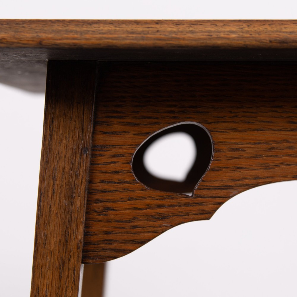 An Arts and Crafts solid oak two-tier side table with tapered legs and heart-shaped pierced motifs along the apron. View VI