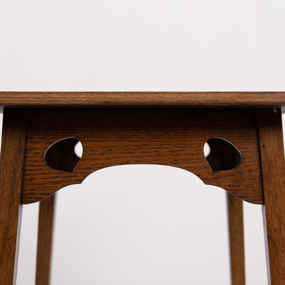 An Arts and Crafts solid oak two-tier side table with tapered legs and heart-shaped pierced motifs along the apron. View VII