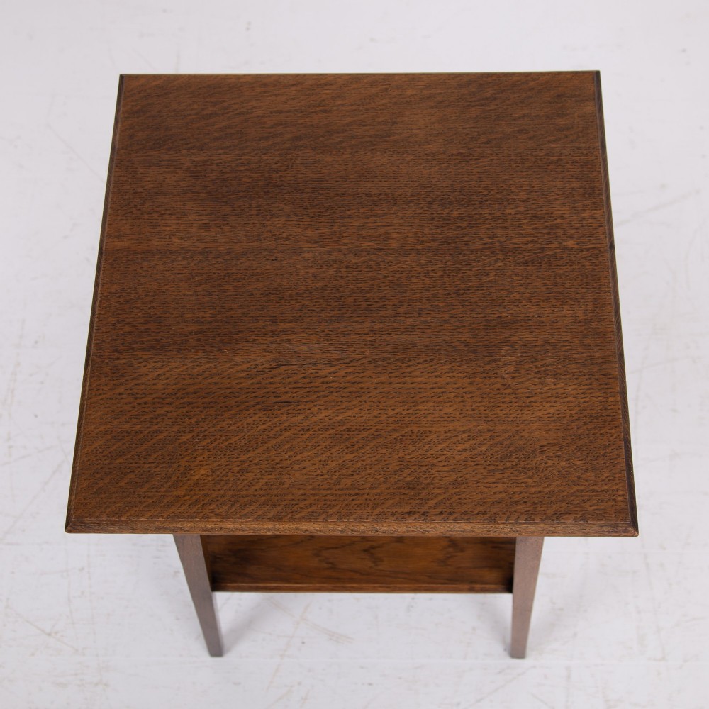 An Arts and Crafts solid oak two-tier side table with tapered legs and heart-shaped pierced motifs along the apron. View X