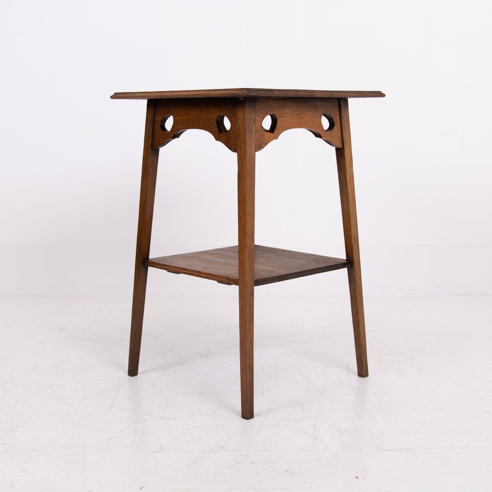 An Arts and Crafts solid oak two-tier side table with tapered legs and heart-shaped pierced motifs along the apron. View XI