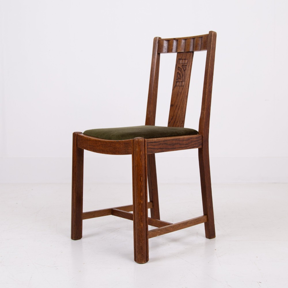 A set of four 1930s oak dining chairs featuring carved back splats, fluted top rails, and green velvet upholstered seats. View IX