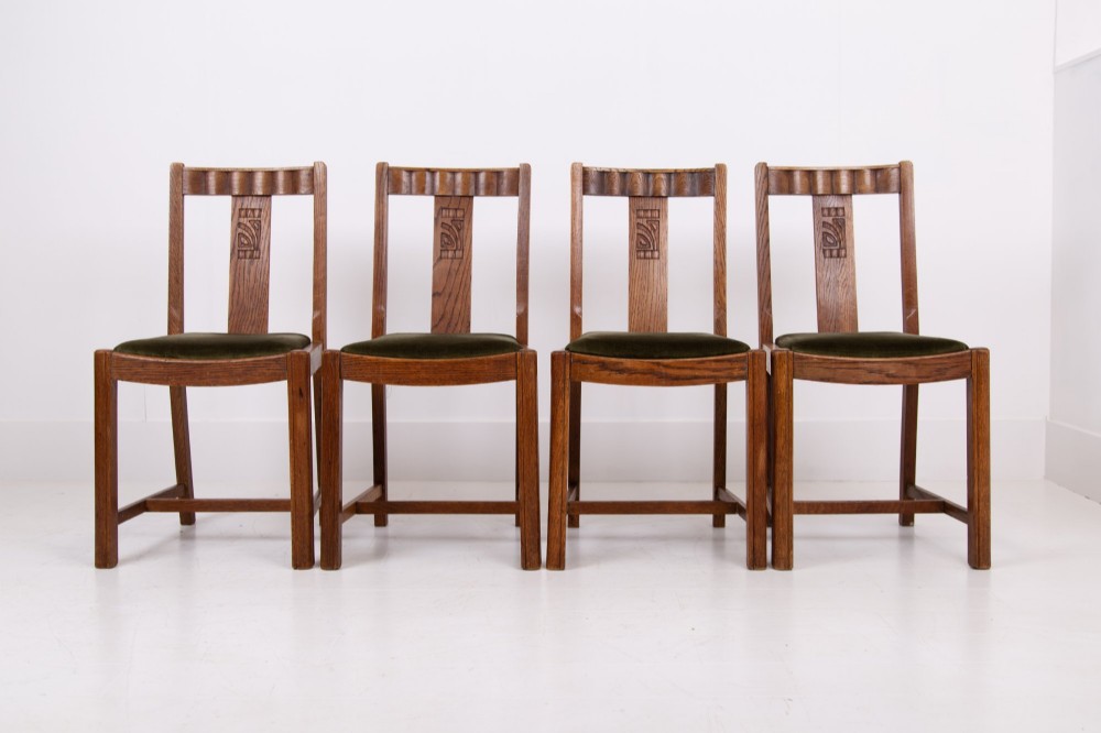 A set of four 1930s oak dining chairs featuring carved back splats, fluted top rails, and green velvet upholstered seats. View XII