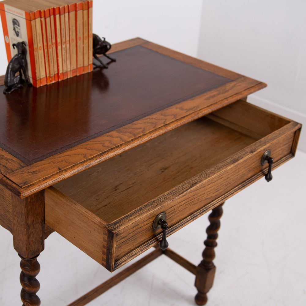 An antique English oak side table featuring a single drawer with metal drop handles, set upon four barley twist legs connected by an H-stretcher base. View II