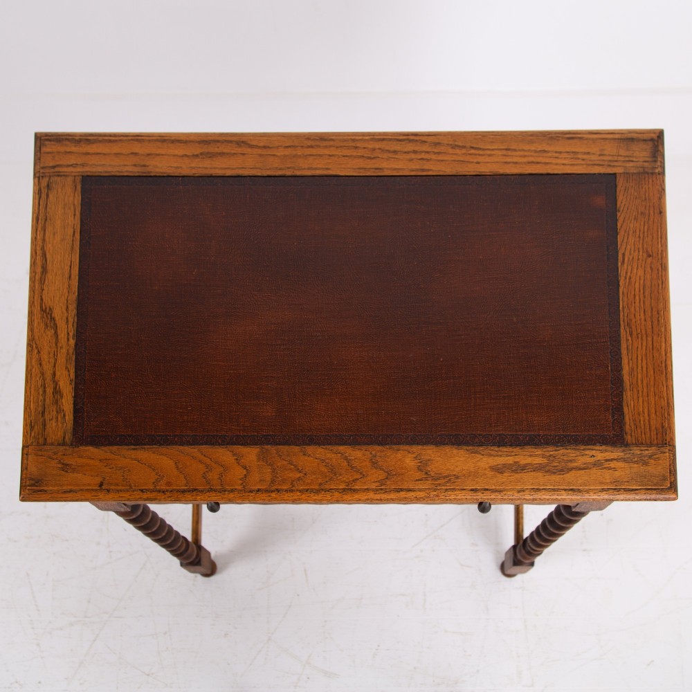 An antique English oak side table featuring a single drawer with metal drop handles, set upon four barley twist legs connected by an H-stretcher base. View V